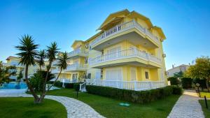 a large yellow building with a balcony next to a pool at Belek King Cleodora Apartment in Belek