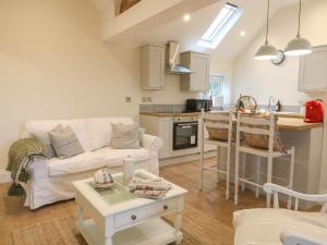 a living room with a white couch and a kitchen at Barn Owl in Ashbourne