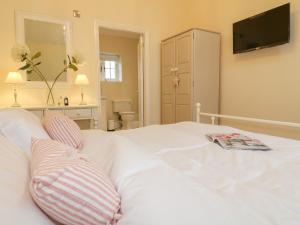 a white bed with two pillows and a magazine on it at March Hare in Ashbourne