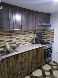 cocina con armarios de madera, fogones y fregadero en Tatev Boutique Cottage, en Tatʼev