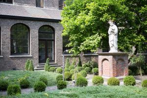 une statue d'une femme dans un jardin devant un bâtiment dans l'établissement Het Rustpunt, à Gand