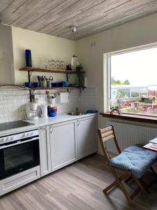 uma cozinha com armários brancos, uma mesa e uma janela em House overlooking the bay in Borgarnesi em Borgarnes