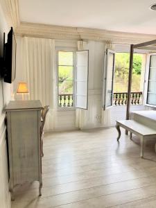 a bedroom with a bed and a table and windows at Hotel Fonte do Fraile in Malpica
