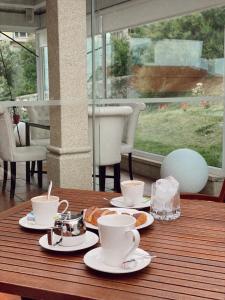 a wooden table with cups and plates of food on it at Hotel Fonte do Fraile in Malpica +16 photos