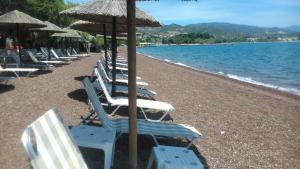 a row of lounge chairs and umbrellas on a beach at Tokalis Boutique Hotel & Spa in Nea Anchialos