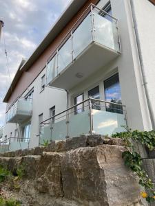a white house with a balcony on top of a rock at Schoko-Apartments mit Bad & Küche in Unterschneidheim