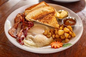 a plate of breakfast food with eggs bacon and toast at Sirenian Bay Resort -Villas & All Inclusive Bungalows in Placencia