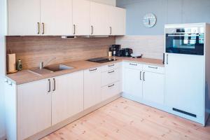 Eine Küche mit weißen Schränken und Holzboden in der Unterkunft Windrose in Barth