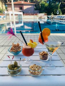 einen Tisch mit Getränken und Schüsseln mit Speisen neben einem Pool in der Unterkunft G&D Hotel Deanna Golf in Milano Marittima