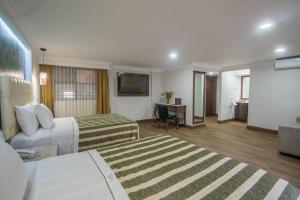 a hotel room with two beds and a desk at Hotel Casino Plaza in Guadalajara