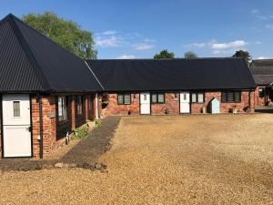 a brick barn with white doors and a black roof at Hunt House Quarters in Kilsby +5 photos