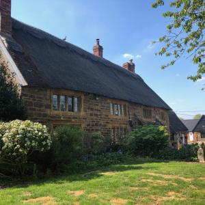 una antigua casa de piedra con techo negro en Hunt House Quarters en Kilsby