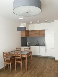 グダニスクにあるMy Old Town Gdańsk - Apartament Barbary 12の白いキャビネット、木製テーブルと椅子付きのキッチンが備わります。
