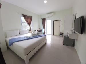 a white bedroom with a large bed and a television at Papangkorn House in Surat Thani