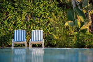 twee blauwe en witte stoelen naast een zwembad bij Hotel Ipomea Club in Capo Vaticano