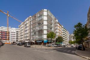 a tall building on a city street with cars parked at Casa da Praia in Armação de Pêra