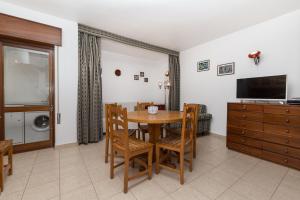 a dining room with a table and chairs and a television at Casa da Praia in Armação de Pêra