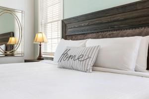 ニューオーリンズにあるHosteeva Brand New Condo with a Pool Steps to St Charles Aveの白いベッド(白い枕、木製のヘッドボード付)