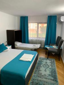 a hotel room with two beds and a chair at Pensiunea Ruxi in Curtea de Argeş