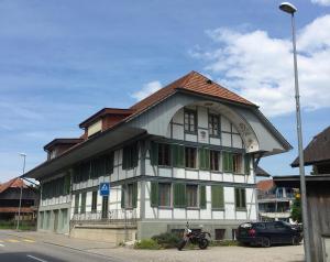 a white and green building with a motorcycle parked in front of it at Modtrip Switzerland in Grünenmatt