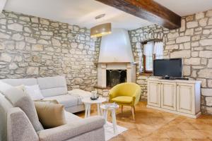 a living room with a couch and a tv and a stone wall at Haus Albino in Kršan
