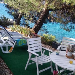 a group of lawn chairs and a table and water at Ana & Marko-Island Ošljak in Island Osljak