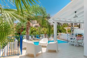 a white patio with white chairs and a pool at Villa Oleandro in Alcamo Marina