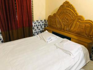 Bett mit einem Kopfteil aus Holz und weißer Bettwäsche in der Unterkunft Hotel Regal Palace in Chittagong + 8 Fotos