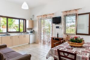 a kitchen and a dining room with a table with a basket of flowers at Villa Oleandro in Alcamo Marina