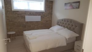 a bed in a bedroom with a brick wall at Orhidea Szuterén Apartman in Győr