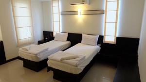 two beds in a room with two windows at K.M. House in Krabi town
