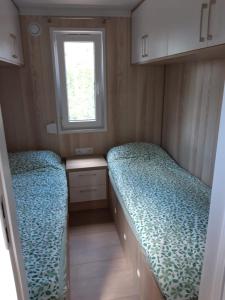 - 2 lits dans une petite chambre avec fenêtre dans l'établissement GARDENIA RAJGRÓD, à Rajgród