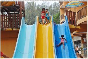drie kinderen spelen op een glijbaan bij een waterpark bij Gold Coast Morib Resort Apartment Ezzy in Kampong Tanjong Pechah