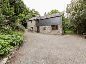 a stone house with a gravel driveway in front of it at Ribby Barn in Lostwithiel