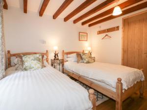 two beds in a room with wooden ceilings at Ribby Barn in Lostwithiel