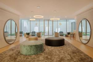 a lobby with a circular table and chairs and mirrors at NH Trento in Trento