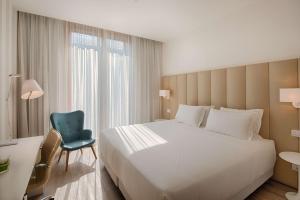 a bedroom with a large bed and a blue chair at NH Trento in Trento