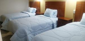 ein Hotelzimmer mit zwei Betten mit weißen Laken in der Unterkunft Hotel Alpamayo Cajamarca in Cajamarca + 28 Fotos