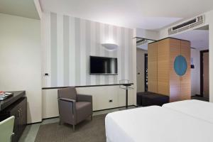 um quarto de hotel com uma cama e uma cadeira e uma televisão em NH Venezia Laguna Palace em Mestre