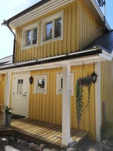 una casa amarilla con porche delantero y puerta en Båtstadsberget Höljes en Höljes