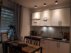 a kitchen with white cabinets and a table with chairs at Apartamenty 33 in Zakopane