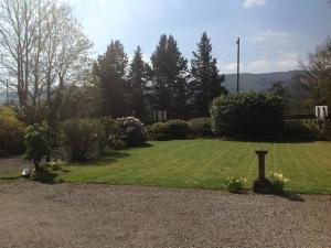 un patio con una gran zona de césped con un taburete dentro en Annslea Guest House en Pitlochry