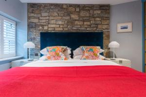 a bedroom with a large bed with a red blanket at Iris 5 Star Gold Award Luxury Cottage in St Ives