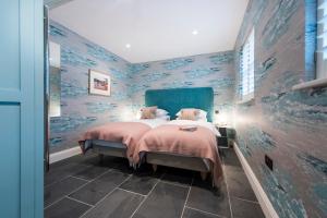a bedroom with a large bed with blue walls at Iris 5 Star Gold Award Luxury Cottage in St Ives +4 photos