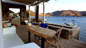 a wooden table and chairs on a dock with a boat at Villa Εν Πλω (Enplo) in Grikos