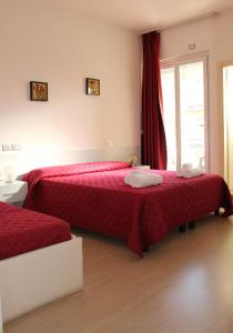 una camera con due letti con lenzuola rosse e una finestra di Hotel Morolli a Rimini