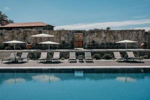 a pool with chairs and umbrellas next to a building at Hotel Paço de Vitorino in Ponte de Lima