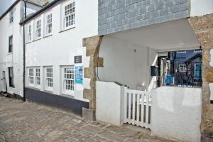 a white building with a white fence next to a street at Iris 5 Star Gold Award Luxury Cottage in St Ives