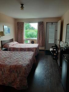 a hotel room with two beds and a window at Motel Vaudreuil in Vaudreuil-Dorion