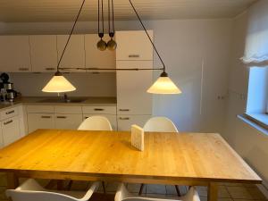 een keuken met een houten tafel en witte stoelen bij Zur Sonnenblume in Gangelt